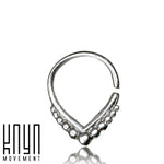 The Triangle Sterling Silver Nose Septum Ring from Kaya Movement is a sleek silver septum piercing designed with a V-shaped detail and adorned with a row of small circular embellishments along the bottom edge. The image features the 18g horseshoe ring isolated on a white background, with the "Kaya Movement" logo in the lower-left corner.