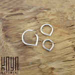 A close-up image showcases three open teardrop-shaped rings of varying sizes arranged on a wooden surface. These silver rings, ideal for multiple piercing applications, feature a minimalist design with the text "Kaya Movement" visible in the bottom left corner.