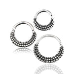 The ITA Seamless Rings in Silver by Kaya Movement are three circular earrings featuring a beaded tribal ethnic design. Each 16 gauge earring showcases a semi-circle of small, raised dots on the bottom half with a smooth top half, creating a gradient effect. Crafted from 925 silver body jewelry ring material, they subtly cast a faint shadow below.