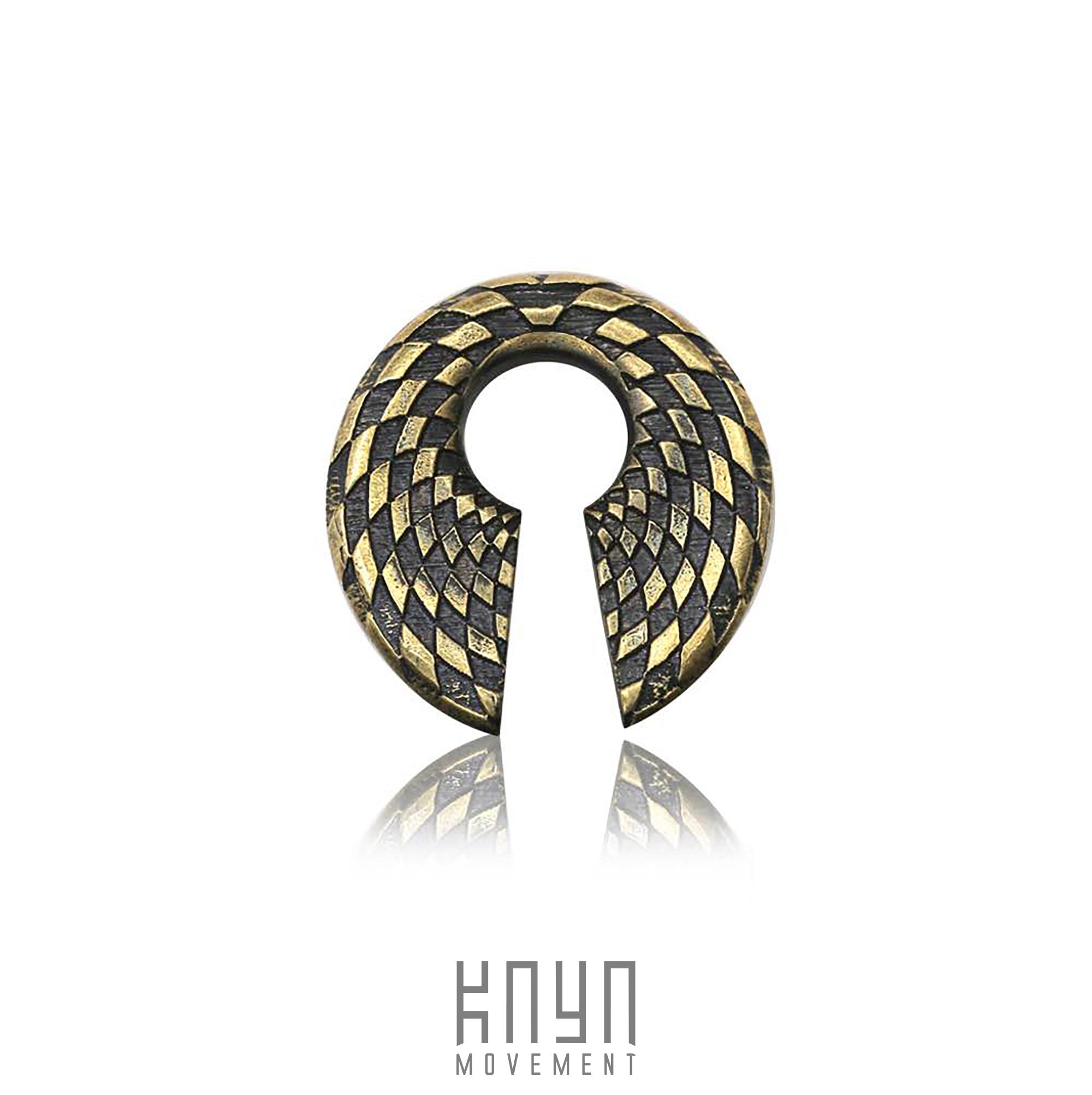 An intricate, metallic pendant named "DAMIER Checkered Hoop Keyhole Ear Weights in Gold | 0 gauge" from Kaya Movement features a geometric, checkered pattern in gold and black. It includes a narrow keyhole opening at the bottom leading to a circular hole in the center. Below the pendant, the text "KNYN MOVEMENT" is displayed.