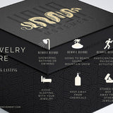 A black box with "Kaya Movement" text on the lid houses the Silver Snake Hoop Earrings With Charm Men - suitable for teat piercing, nose septum, helix piercing, and daith piercing. The box includes jewelry care tips: remove before showering, going to the beach, and physical activities; avoid sleeping with jewelry like your septum piercing; keep away from chemicals; store in a box away from other jewelry.