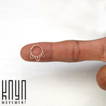 A close-up of a person's finger holding a small, intricate ring. The MAWAR Lotus Clicker Septum Ring, crafted from surgical steel with a rose gold PVD coating, features a delicate floral design. The image has a white background and the text "Kaya Movement" is displayed in the lower left corner.