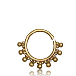 A close-up of the BRAI Seamless Septum Ring in Gold by Kaya Movement, designed in a circular shape with an open end. It is adorned with small spherical beads along the bottom half, showcasing its tribal ethnic design. The background is white and uncluttered, making the details of this 18 gauge gold brass body jewelry stand out.