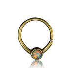 The Kaya Movement NAE Seamless Septum Ring in Gold & Opal | 18 gauge is an antique gold brass body jewelry piece featuring a small, circular, natural opal gemstone at its center. This elegant and minimalist ring has a simple, closed design with a slight opening and showcases an opal stone that radiates vibrant colors, making it perfect for versatile use in piercings.