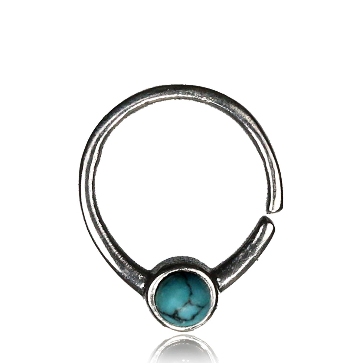 Introducing the NAE Seamless Septum Ring in Silver & Turquoise by Kaya Movement. This 18 gauge septum ring showcases an open design with a single round natural blue turquoise gemstone centrally set. Crafted from 925 sterling silver, the ring features a smooth finish and securely encloses the vibrant gemstone. Its minimalist style and adjustable nature make it a versatile piece of body jewelry suitable for any occasion.
