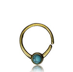 The "NAE Seamless Septum Ring in Gold & Turquoise" by Kaya Movement, an 18-gauge minimalist piece, features a natural blue turquoise stone set at its center and is showcased against a white background. The bold, round turquoise stands out beautifully against the gold band.