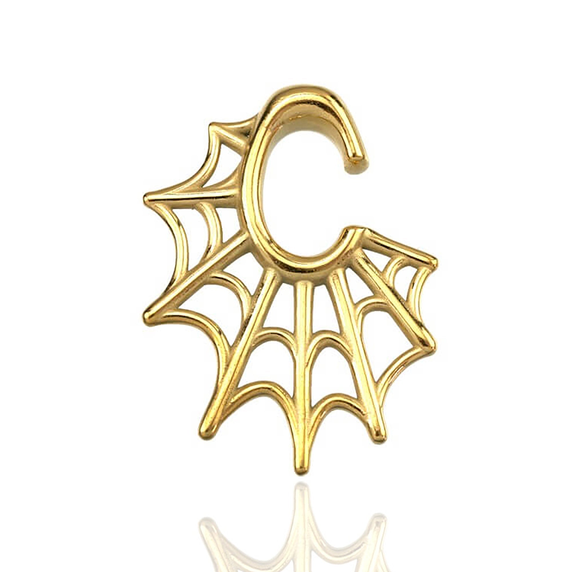 The Spider Web Gothic Steel Ear Hangers in Gold, designed by Kaya Movement, feature an elaborate spider web pattern intertwined with a letter "C" shape at the bottom. This intricate design lends a delicate and ornate appearance to the 2 gauge ear hangers, beautifully showcased against a white background with a slight reflection underneath.