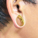 A close-up of an ear with a teardrop-shaped Kaya Movement surgical steel ear tunnel inserted through the earlobe, showcasing a stretched ear piercing. The Teardrop Tunnel has smooth and polished edges, adding a touch of elegance to the stretched lobe.
