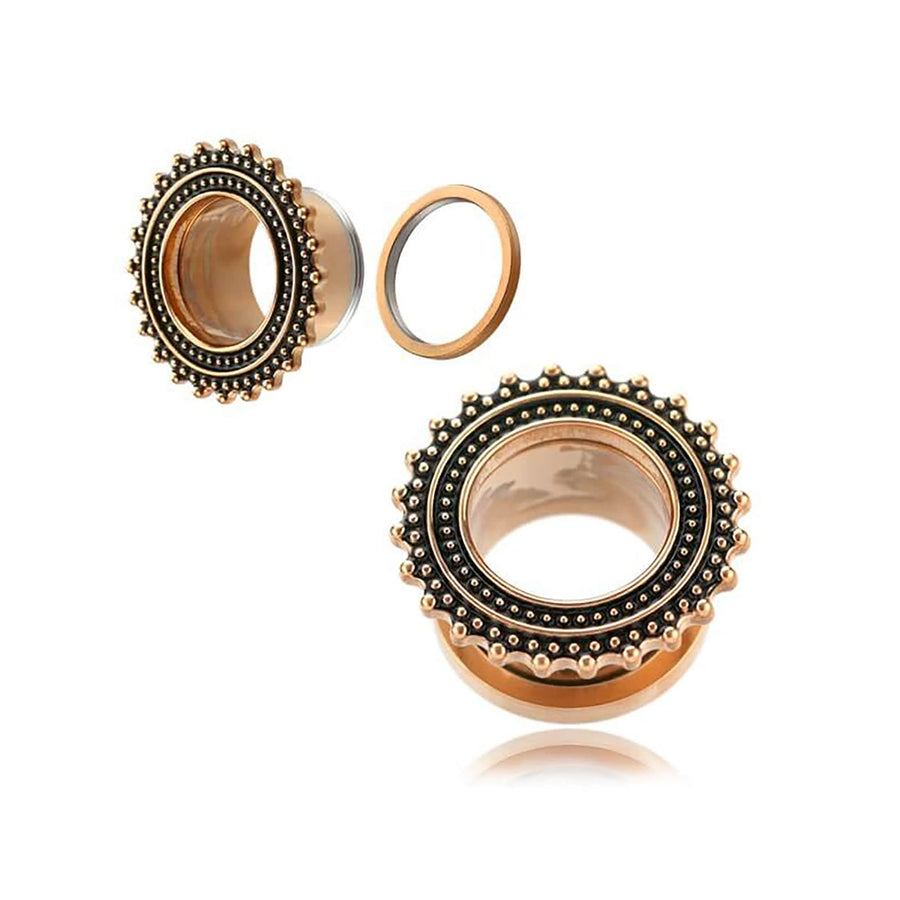 An image showcasing two Rose gold plugs from Kaya Movement, designed for small gauged ears, features a black beaded design around the edges. These stainless steel Flesh Tunnel piercings glisten with a metallic finish and intricate details. One plug is shown with the back detached, while the other remains fully assembled.