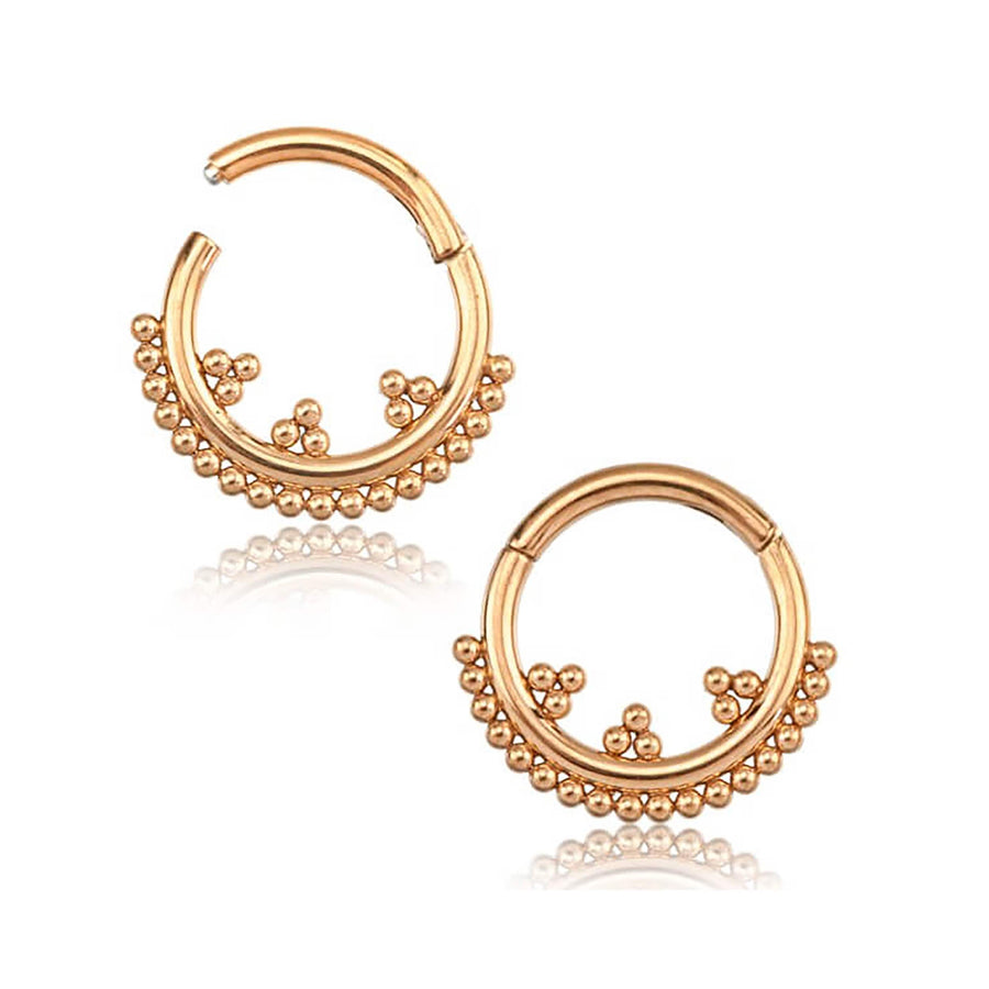 A pair of circular gold hoop earrings featuring intricate beaded detailing along the bottom half, reminiscent of the Kaya Movement Rose Gold Septum Clicker 16g - 8mm Cute Hinged Septum Ring. The earrings have a polished finish and are displayed against a white background, with a faint reflection beneath them.