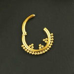 The Kaya Movement Gold Septum Clicker 16g - 8mm Cute Hinged Septum Ring rests elegantly against a black background, showcasing its intricate detailing. Adorned with small spherical ornaments along the bottom curve, this piece boasts a traditional and decorative appearance, making it perfect for enhancing any nose piercing.