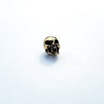 A small metallic skull sculpture sits on a plain white surface. The finely detailed skull boasts a shiny, reflective finish, reminiscent of the intricate Viking Hair Beads Accessories - Alien Vampire Carved Skull Dreadlocks Beads Jewellery by Kaya Movement, which gives it a striking appearance against the stark white background.