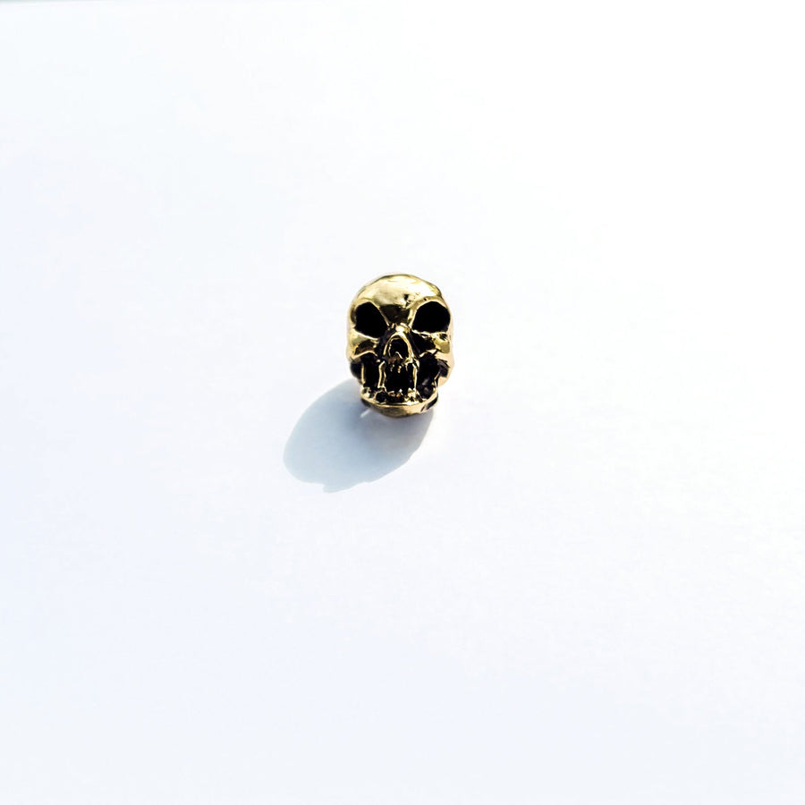 The Viking Hair Beads Accessories from Kaya Movement, featuring an intricately carved Alien Vampire Skull in metallic gold, make a perfect addition for adding a unique touch to dreadlocks. Placed on a white background, subtle shadows fall to the left and behind the charm.
