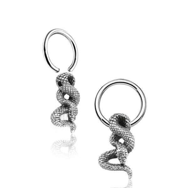 The Silver Snake Hoop Earrings With Charm from Kaya Movement feature intricately designed snake pendants that hang from silver hoops. The snakes are textured to resemble scales and are coiled in a striking, elegant fashion. Perfect for various piercings such as teat, nose septum, helix, and daith piercings (14g), these goth anime-inspired earrings have a shiny, polished finish.