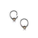 A small, 18g silver septum ring featuring circular opal gemstones set in the center, known as the Opal nose ring from Kaya Movement. The opals exhibit a stunning range of colors with prominent blue and orange hues, reminiscent of elegant body jewelry. The septum ring is displayed against a plain white background.