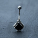 A beautiful belly button ring from Kaya Movement, crafted with real seashell and mother of pearl, is showcased against a dark grey background. This stunning piece of body jewelry features a silver 925 setting and a surgical steel navel barbell, perfect for navel piercings and summer belly dance. Enjoy fast delivery when you order this exquisite 14g barbell today.