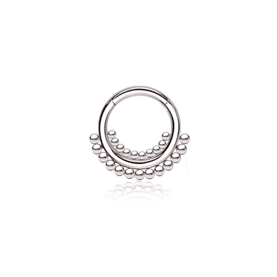 The "Bohra" septum jewelry from Kaya Movement features a delicate, silver circular design made of 316L steel. It showcases minimalist elegance with a larger circular form adorned with evenly spaced small balls along the bottom half. The septum has a polished, reflective surface and an open design at the top, measuring 1.2mm in gauge and 8mm in diameter.