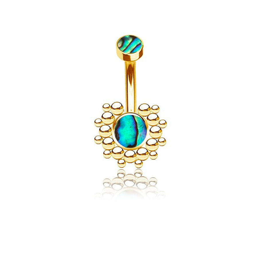 The Solis Navel Piercing by Kaya Movement showcases a geometric golden design with boho shine. The exquisite piece features a small, round green-blue abalone shell at the top and a larger matching gemstone at the bottom, encircled by a decorative array of small gold beads. Its intricate craftsmanship and gleaming gold finish make this striking accessory stand out beautifully against a white background.