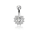 Introducing the Sira Navel Piercing by Kaya Movement, a stunning belly button ring that features a geometric silver design. This modern piece boasts a large central gemstone surrounded by smaller beads arranged in a circular pattern and is accentuated with a sparkling zircon on the curved barbell. With its brilliant finish and clear gemstones, it's perfect for navel piercings at 10mm length and 1.6mm gauge (14g).