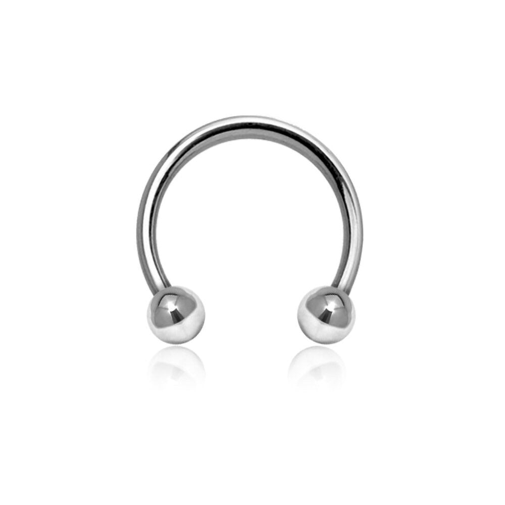 The 316L Steel Silvered Circular Barbell Septum "Argia" by Kaya Movement is a polished silver horseshoe-shaped piercing ring, available in 1.2mm gauge with diameters of 6mm, 8mm, and 10mm. It features two spherical beads at each end and boasts a shiny, reflective surface, set against a plain white background—an ideal piece for minimalist jewelry lovers and perfect for nose piercings as well as tragus and lobe adornments.