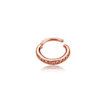 The Hinged Septum Ring Clicker from Kaya Movement features a gold-toned hoop set with multiple small, clear gemstones along its outer curve. Reminiscent of a rose gold septum ring, this 16g cubic zirconia earring is designed with an open end that gives it a semi-circular shape and elegant appearance. Its sleek design is perfect for conch, daith, helix, cartilage, or rook piercings, and the reflection can be seen beneath it.