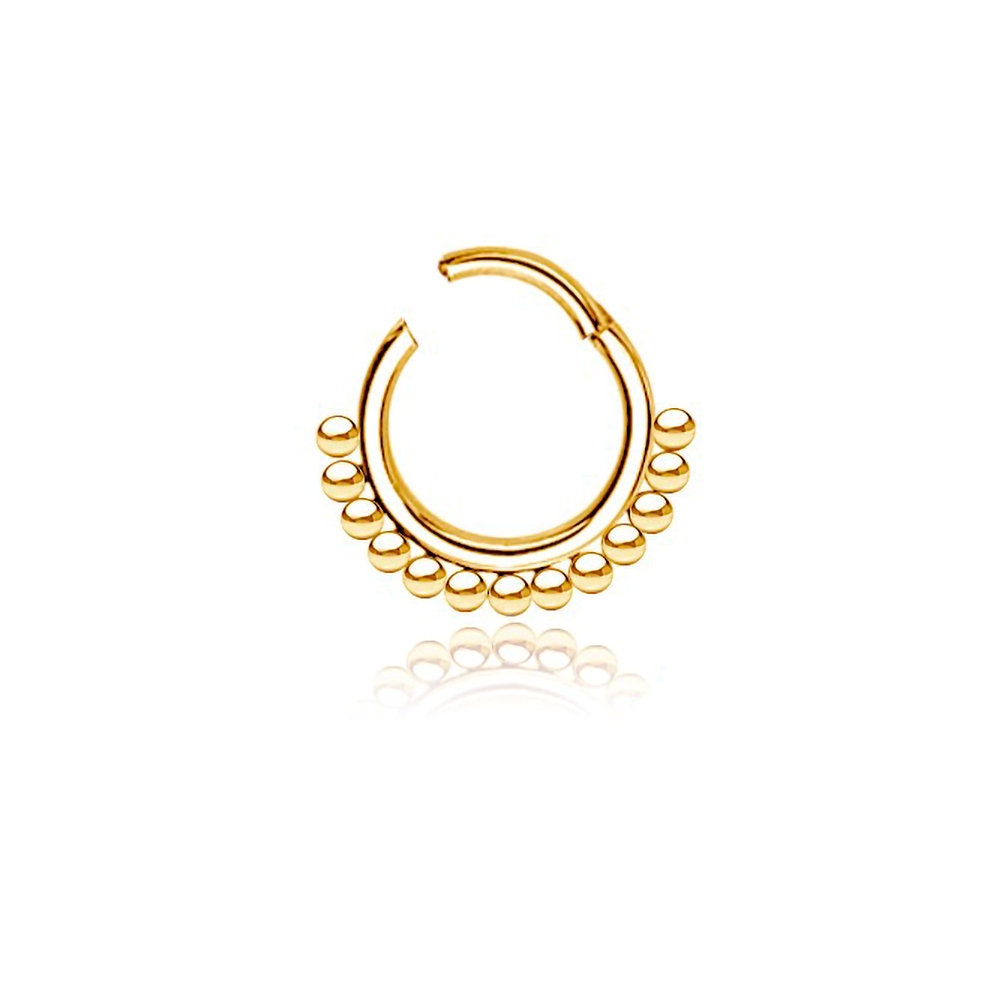 The Kaya Movement's Simple Ethnic Septum in 316L Gold PVD Steel "Etna" is an elegant and traditional design, featuring a delicate open circular design with small, evenly spaced bead-like decorations along the bottom edge. This exquisite septum jewelry, boasting a stunning Gold PVD finish, is displayed against a plain white background, evoking a touch of ethnic art. The ring measures 1.2mm in gauge and 8mm in diameter.

