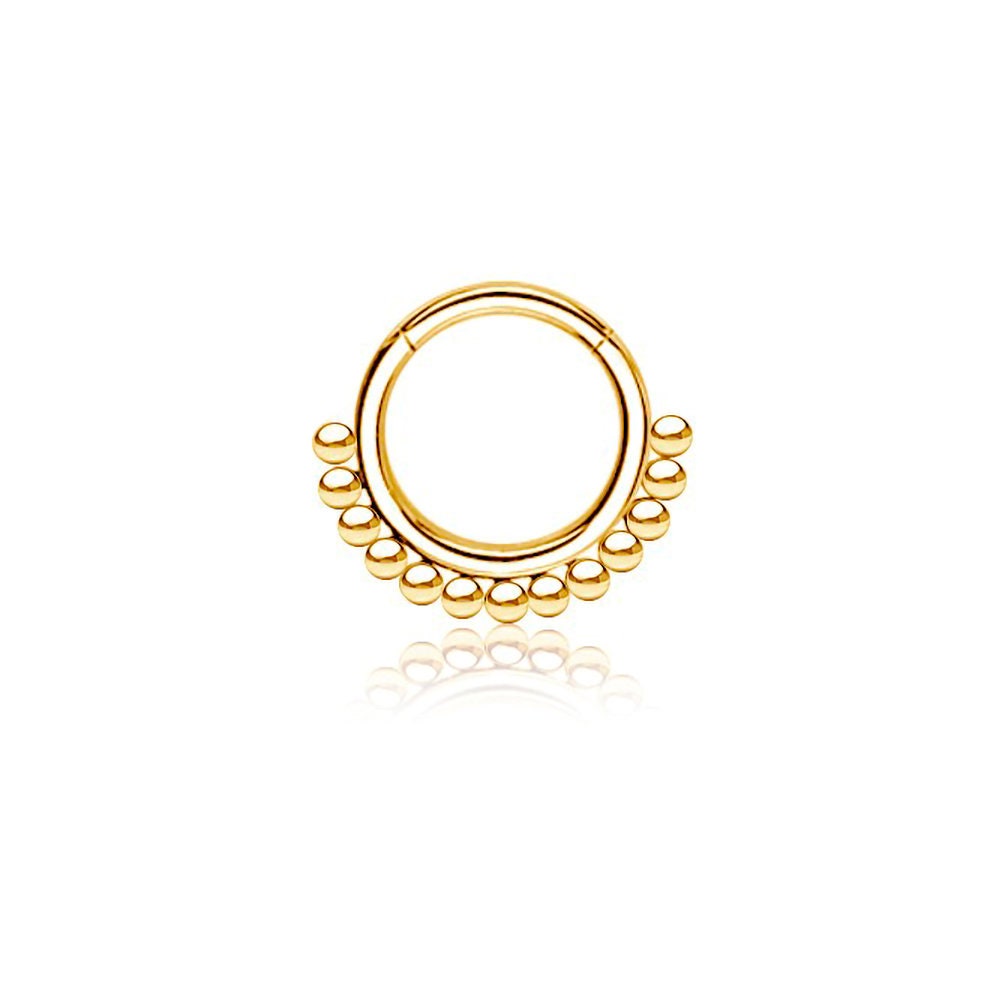 Introducing the "Etna" by Kaya Movement: an elegant and traditional decorative nose ring crafted from 316L Gold PVD Steel. This simple ethnic septum jewelry features a circular design with a row of small, evenly spaced gold beads along the bottom edge. Measuring 1.2mm in gauge and 8mm in diameter, this shiny piece is showcased against a white background, perfectly capturing the essence of ethnic art.