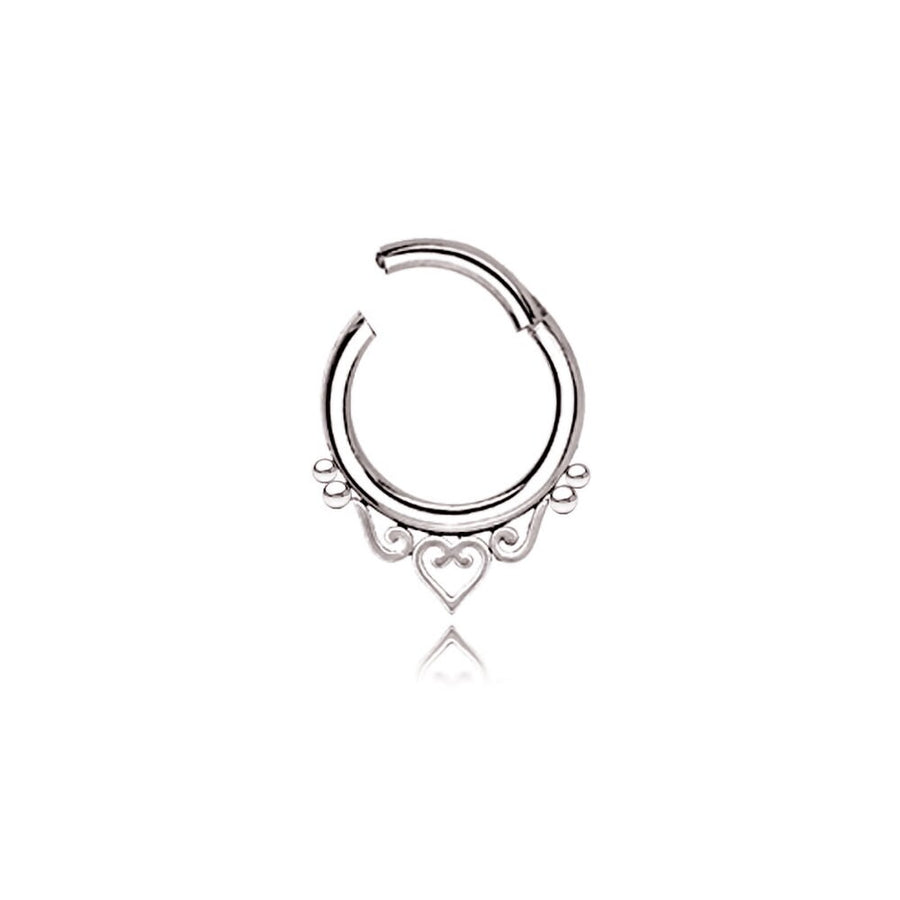 The Kaya Movement's Minimalist Mandala-Inspired Septum in 316L Steel Silver Look "Zura" showcases an intricate design with small loops and a central heart shape. This silver septum ring, available in 1.2mm gauge and diameters of 6mm, 8mm, or 10mm, is open at the top for easy insertion and removal. Against a plain white background, this minimalist jewelry piece truly stands out.