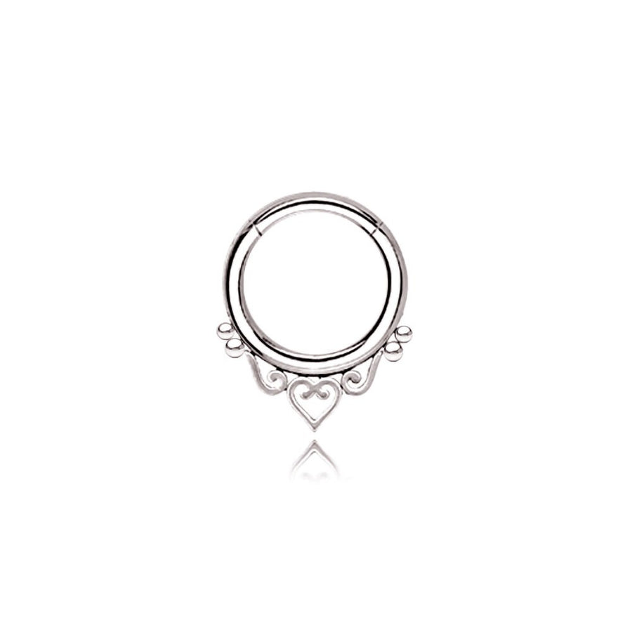 A minimalist septum ring from Kaya Movement, inspired by mandala designs and crafted from high-quality 316L steel, features a silver look under the name "Zura." The design showcases delicate heart detailing at the bottom and includes two small loops flanking the central heart, adding ornamental elegance to the piece. Available in 1.2mm gauge with diameters of 6mm, 8mm, or 10mm, this septum ring stands out against a white background for an eye-catching focal point.