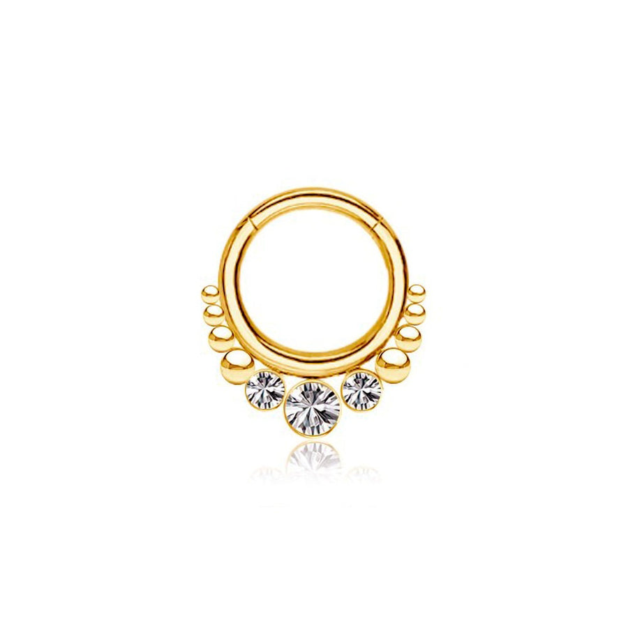 The TriZa Gold PVD Septum with Three Sparkling Zirconias by Kaya Movement is a refined gold hoop earring adorned with small circular designs along the bottom and highlighted by three larger, round sparkling zirconias at the center. The earring is displayed on a white background.